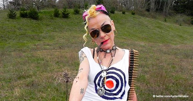 Chrese Evans with curly hair, sunglasses, and patterned shirt stands in a grassy field. They wear necklaces and pink headphones with a confident pose.