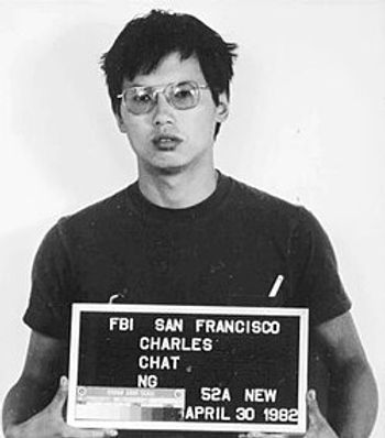 A person with glasses holds a sign displaying text "FBI San Francisco Charles Chat Ng April 30 1982," standing against a plain background.