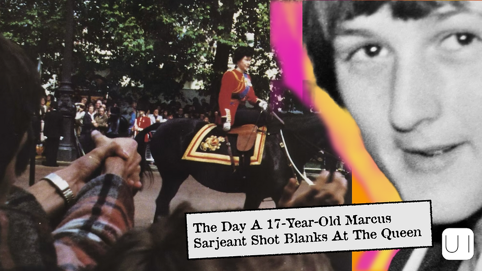 A person in a red uniform on horseback in a parade. Crowd in background. Foreground shows clasped hands, suggesting excitement.