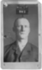 Stern-faced bald man in a dark suit, serious vintage portrait.