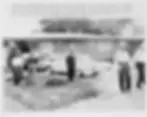 Four men stand outside a house with cars parked in front. Two of them wear hats, and two wear helmets. Text details an event at the location.