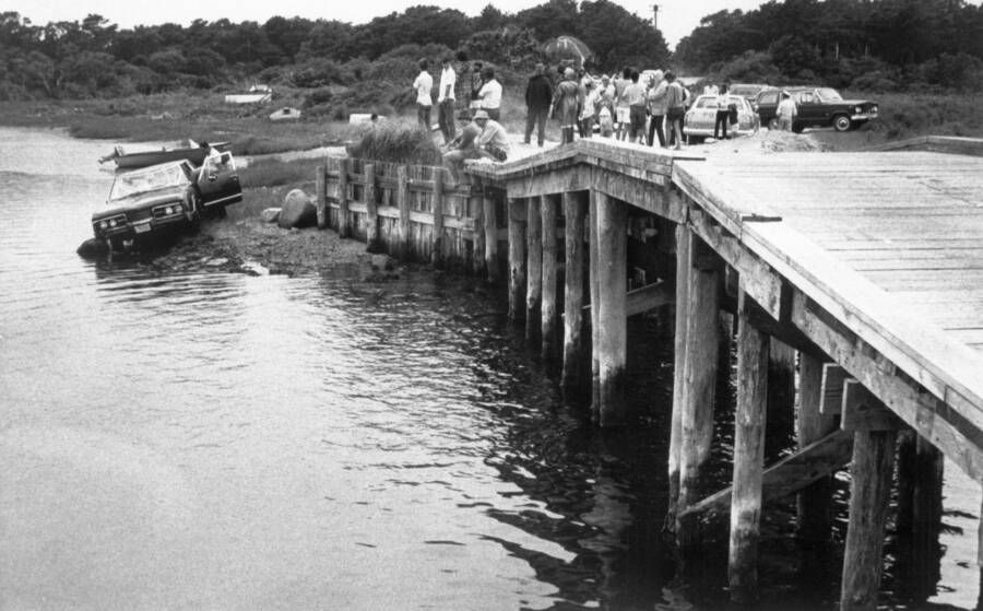 Spectators look on as the car that Ted Kennedy crashed into the pond is pulled from the water, July 24, 1969.