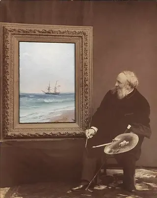 Bearded artist with palette beside seascape painting of ship on beach.