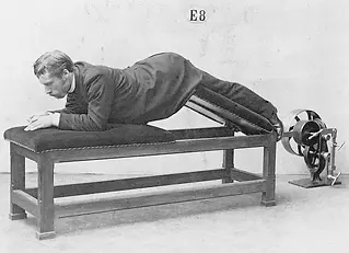 Man in suit exercising on plank machine, with visible text E8.