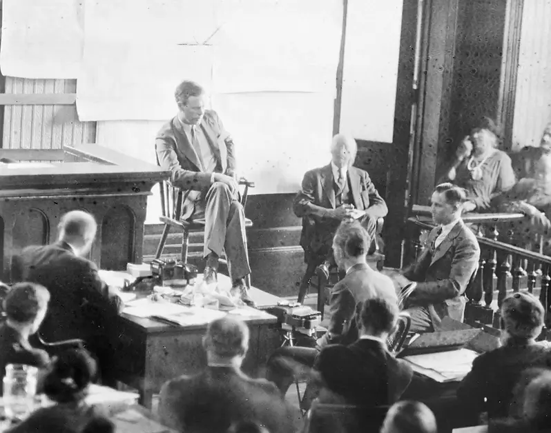 A courtroom scene with a man seated in the witness box, others at desks, and spectators in the gallery. The mood is serious and formal.