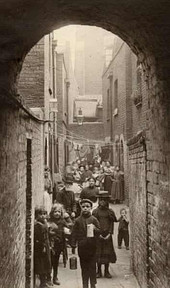 Crowded historical urban alley filled with many people and children.