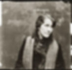 Sepia-toned image of a woman looking sideways, wearing a fur-lined coat and scarf. Text above her reads "20 Mrs Osbourne." Neutral background.