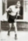 A vintage photo of a boxer in a fighting stance wearing shorts with a Star of David. Brick wall background, sepia tone adds a historic feel.