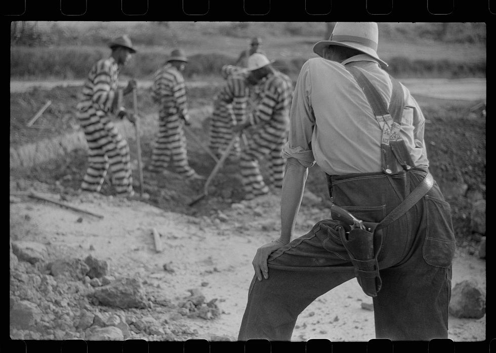 Convict laborers in striped uniforms working under armed guard in Oglethorpe County, Georgia.