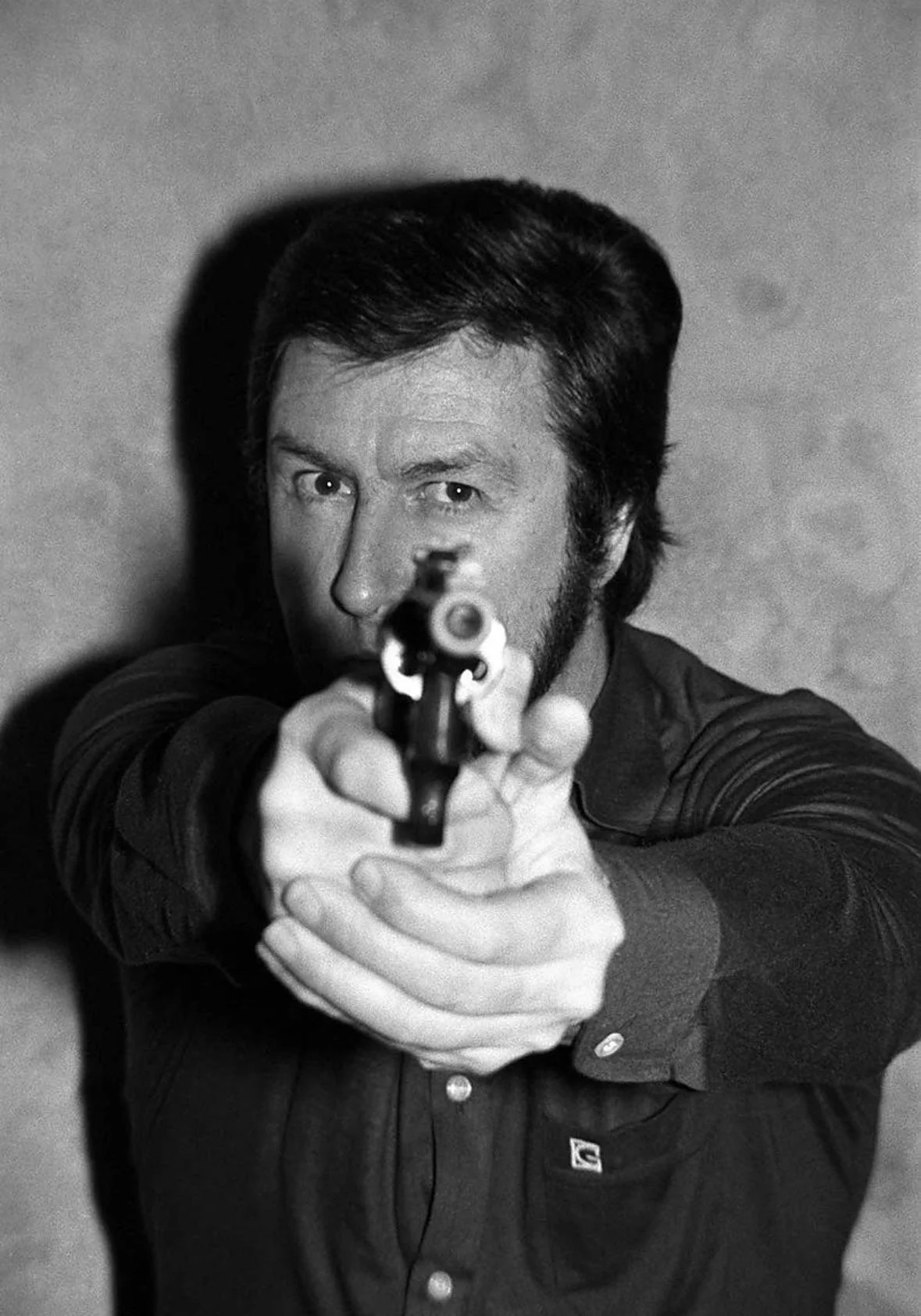 Man pointing a gun with a fierce look to the camera 