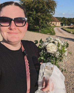 Molly holds brides bouquet, veil and champagne whilst looking proud