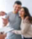 Young couple, man and woman, smiling as they receive keys to their new home from a realtor.