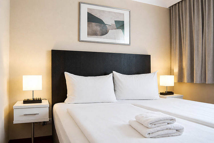 Gemütliches Doppelzimmer im Hotel Kramer in Villach mit bezogenem Bett und Nachttischlampen.