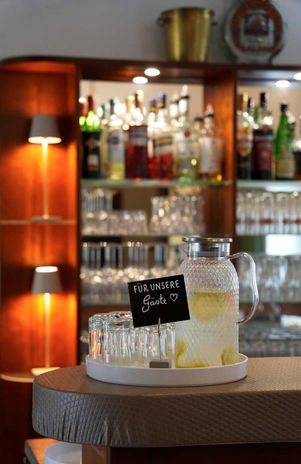 Karaffe mit Zitronenwasser und Gläsern auf einer Bar.
