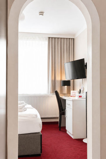 Doppelzimmer Basic mit Schreibtisch, Fernseher und rotem Teppich
