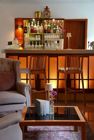 Beleuchtete Bar mit Hockern und Lounge-Bereich