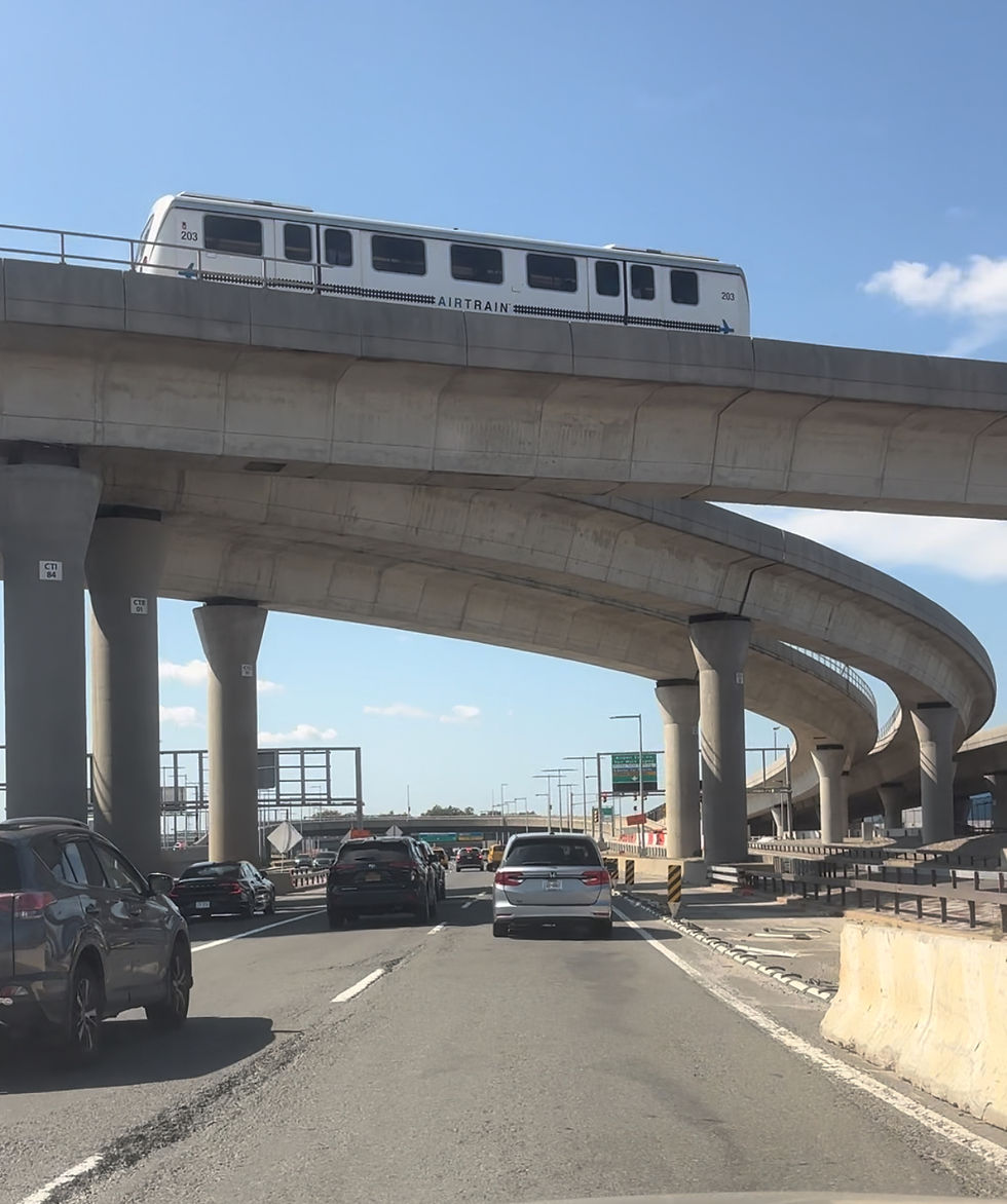 vehicles exiting jfk airport while the Air Train runs on the tracks above taking passengers to terminals