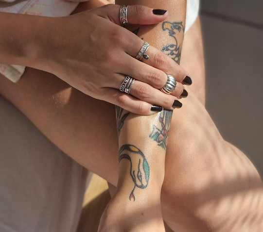 Óleo vegetal sendo passado em um braço feminino tatuado, realçando suas cores