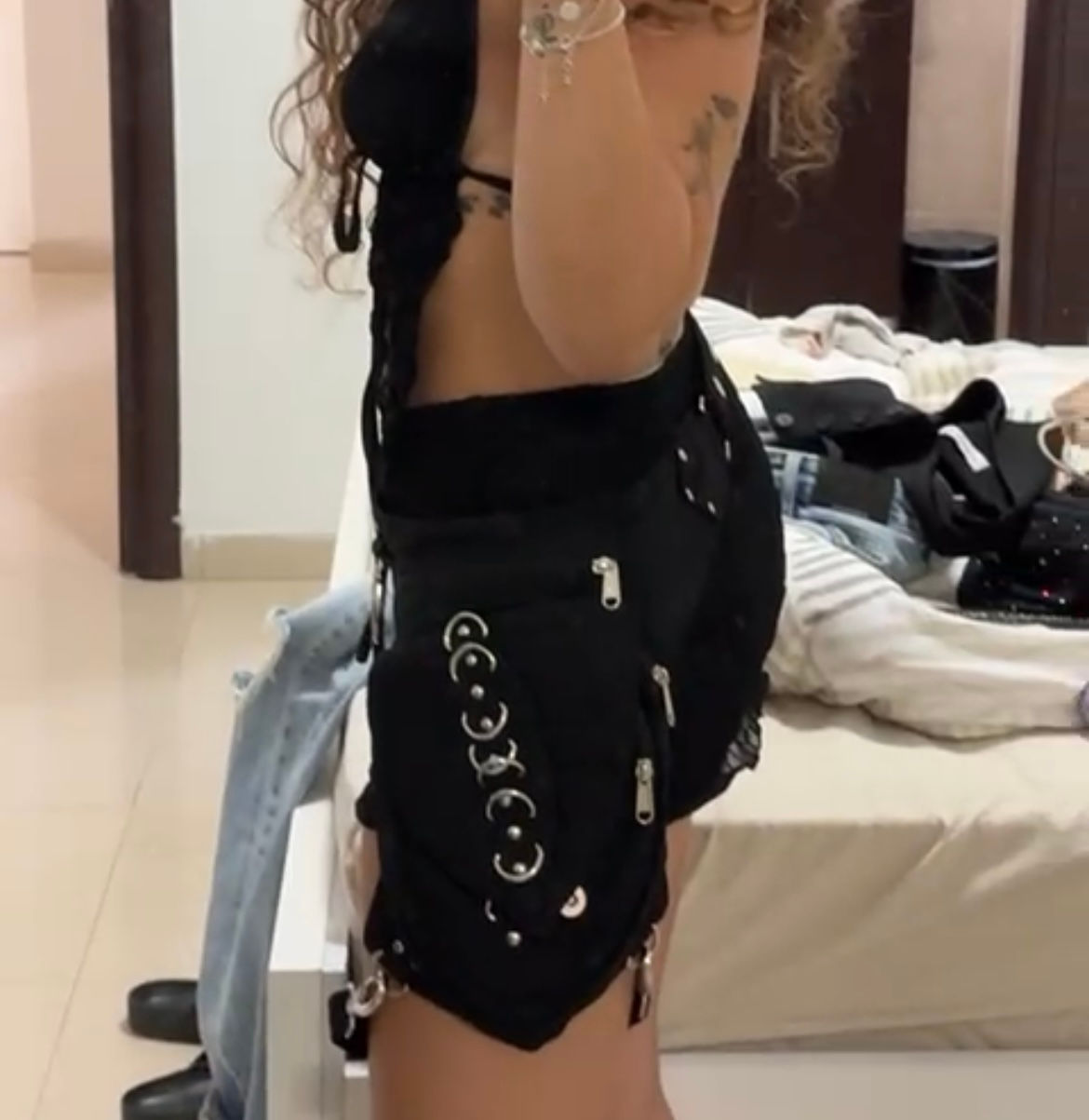 אישה לובשת חצאית שחורה קצרה עם אבזמים