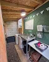 Campsite washing‑up area with stainless steel sink, under‑counter fridge and freezer, worktop and information board at Dove Cote Lodge Camping in Selby, North Yorkshire.