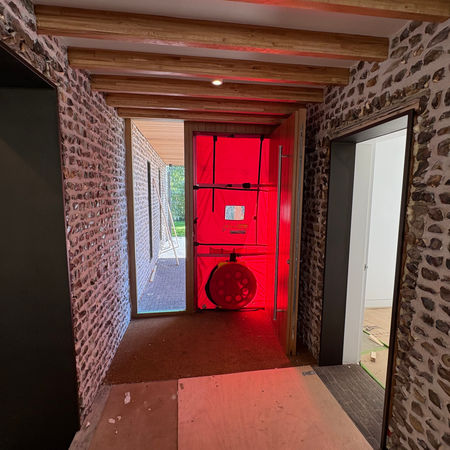 red blower-door screen and fan inside hallway during air permeability test