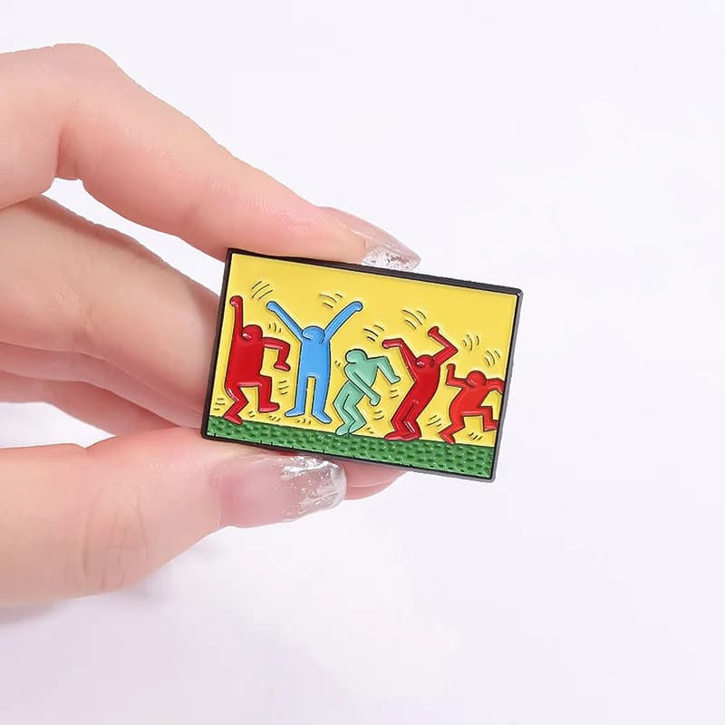 Pin émaillé coloré représentant une silhouette dansante, inspirée du style graffiti de Keith Haring. Accessoire artistique