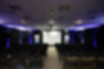 A class room style conference setup with a large screen in front.