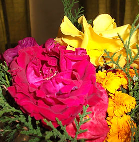 Bouquet of pink rose, yellow rose, and marigolds arranged with green foliage.