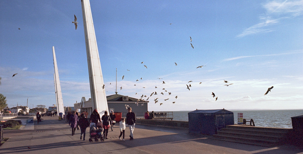 Seagulls circling over some people on the promenade at Southend.