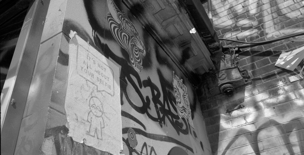 Black and white photograph of graffiti and bill posters.