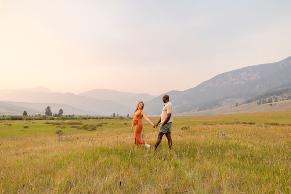 Expecting parents sharing a romantic moment during a maternity photo session surrounded by mountains and warm evening light in Big Sky, Montana.