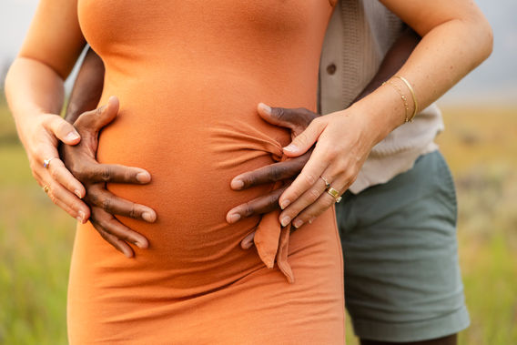 Expecting parents sharing a romantic moment during a maternity photo session surrounded by mountains and warm evening light in Big Sky, Montana.