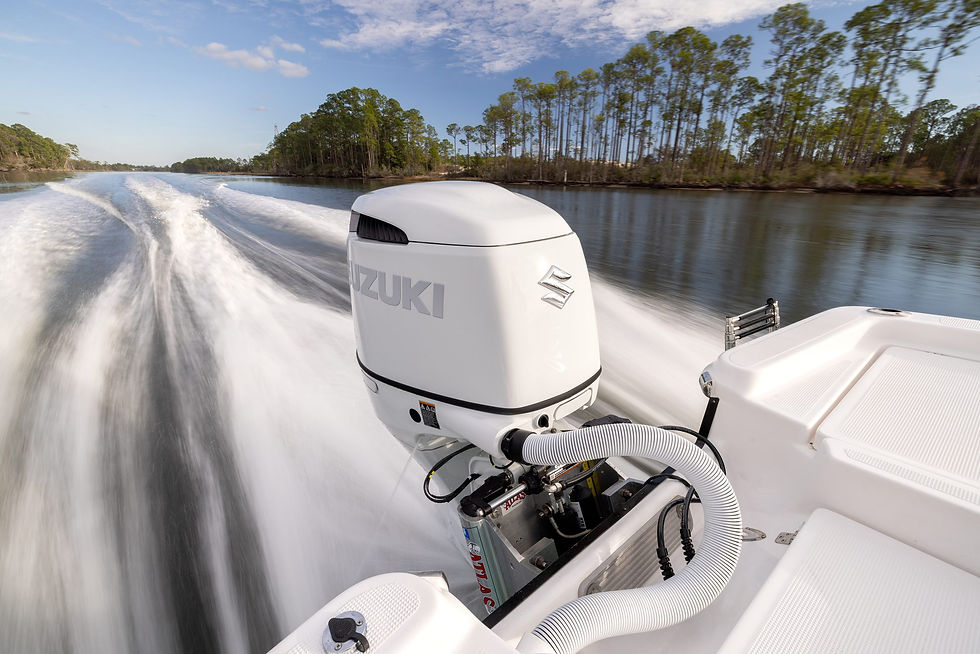 Boat with a Suzuki engine speeds through a river, leaving white wake trails. Trees line the water under a bright blue sky.