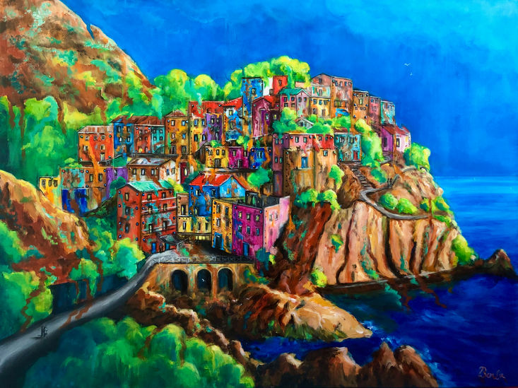 A town with colorful houses and trees on a mountain and by the sea. 