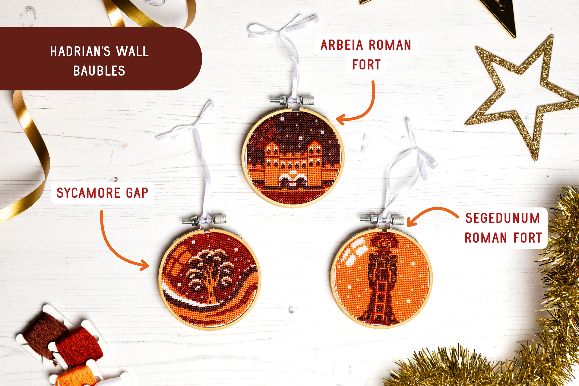 hadrians wall cross stitch christmas baubles in organe tones featuring sycamore gap, segedunum and arbeia roman forts