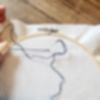 completing a navy french knot on white aida with embroidery hoop