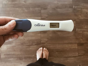girl holding white and blue pregnancy test that says pregnant