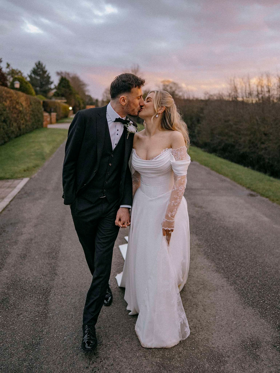 Bonnie and Oliver walking together at Brackenborough Lakes after their wedding ceremony