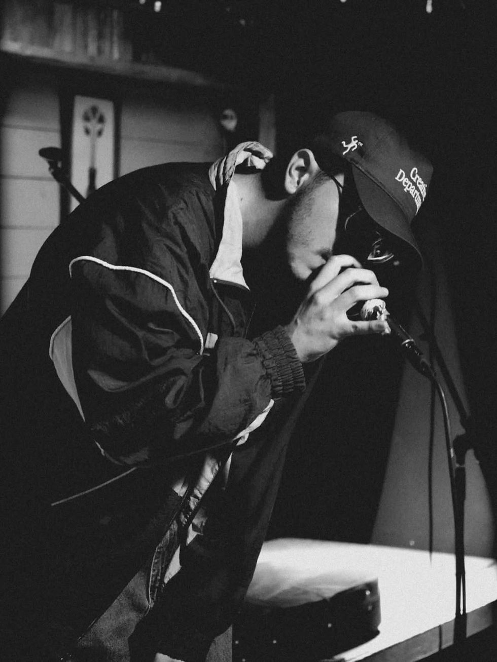 Andrømeda performing live on stage, leaning into the microphone in a black and white photo
