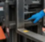 Gros plan sur l'inspection du talon d'une fourche de chariot élévateur VMAX — vérification manuelle de l'usure et des fissures, contrôle conforme norme ISO 5057