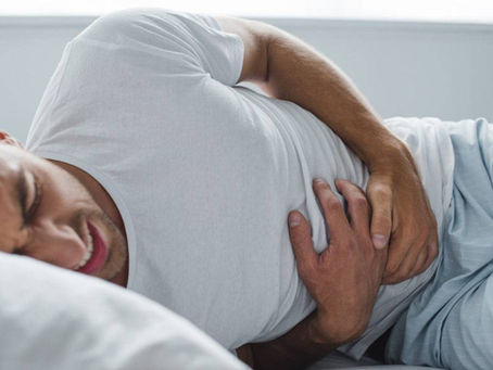 man laying down in bed in pain with H. Pylori