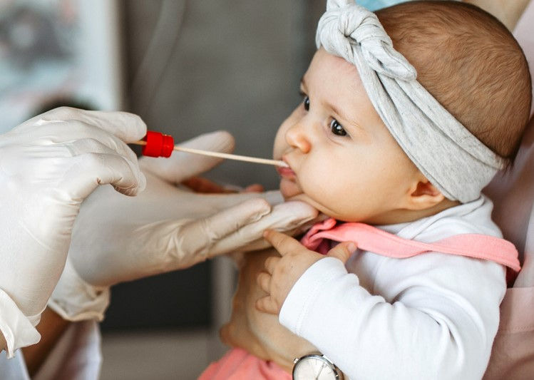 Nursing getting saliva from infant during congenital cytomegalovirus (cCMV) screening
