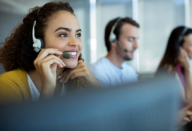 A woman in a call center with a headset on smiling