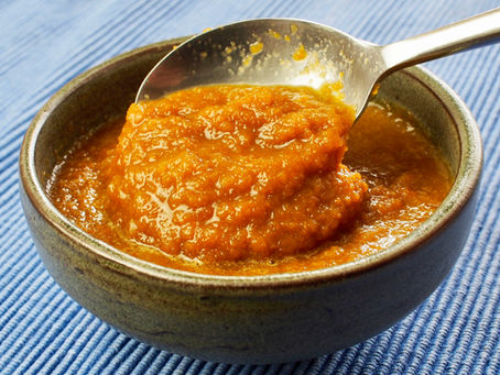 A spoon scoops Japanese onion sauce from a ceramic bowl on a blue striped cloth, creating a warm and appetizing scene.