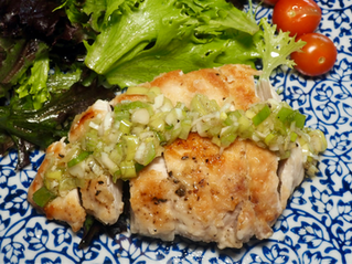 Fried chicken with green onion garnish, mixed greens, and cherry tomatoes on a blue patterned plate, set on a blue placemat.