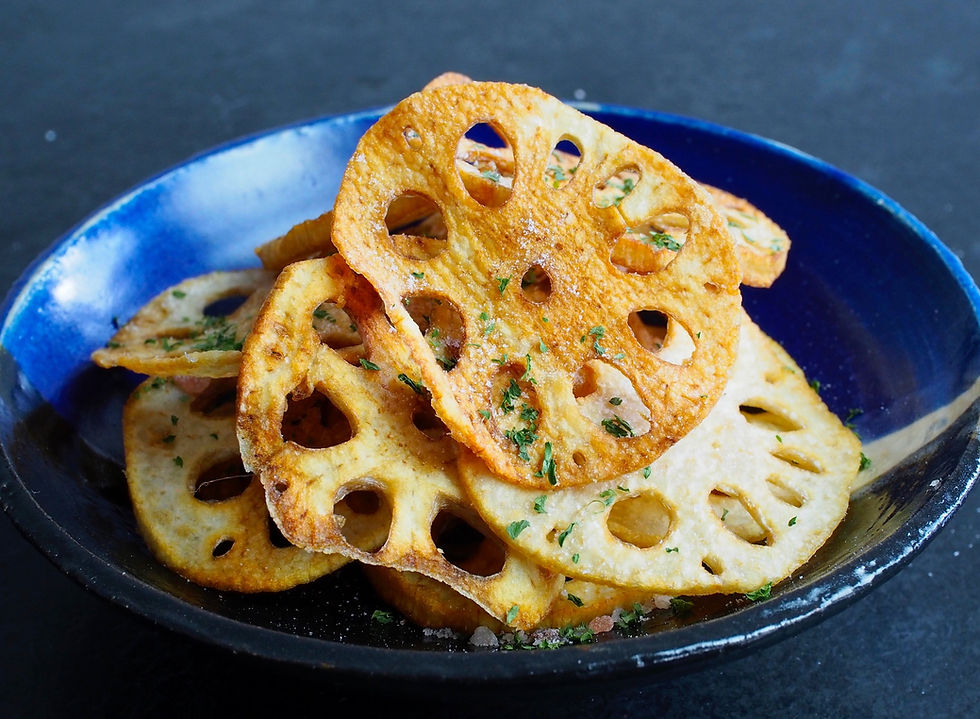 Crispy fried lotus root slices with herbs piled in a blue bowl on a dark background.