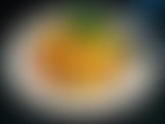 Colorful mango salad with carrots, tomatoes, green beans, and cilantro on a striped plate. Silver utensils on a dark surface.