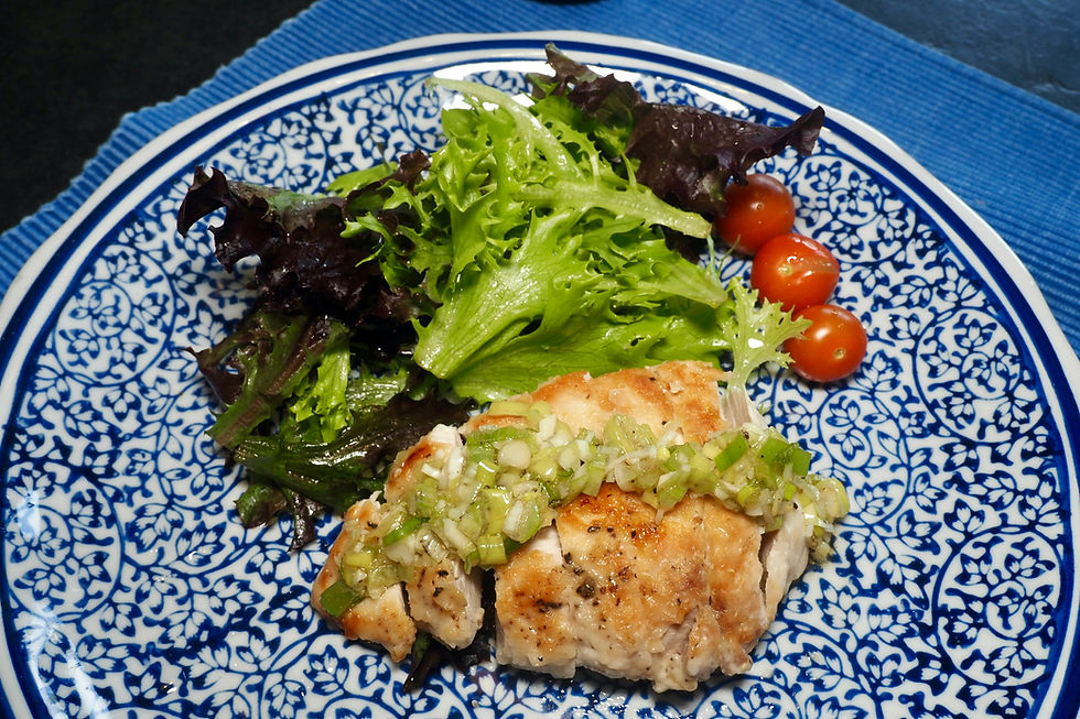 Fried chicken with green onion garnish, mixed greens, and cherry tomatoes on a blue patterned plate, set on a blue placemat.