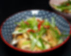 A bowl of stir-fried mushrooms with green onions and red peppers, in a patterned blue bowl with a red rim, on a dark background. donburi.