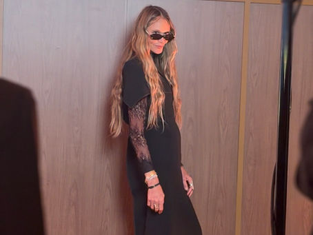 Elle Macpherson in black gown and sunglasses poses before Welle Australia and Chemist Warehouse backdrop at an event.
